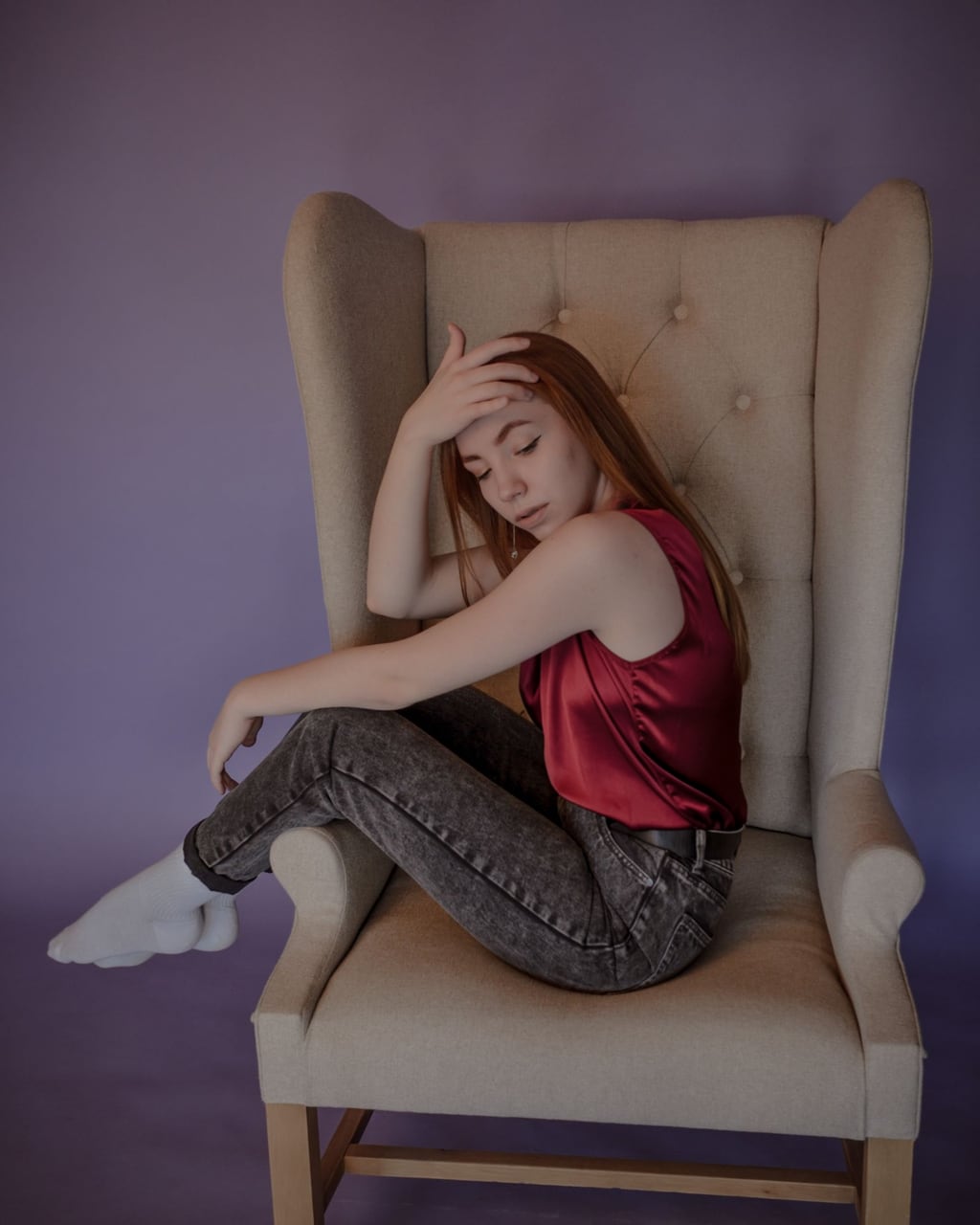 A woman on an armchair, her black top clicked and replaced with a red silk blouse
